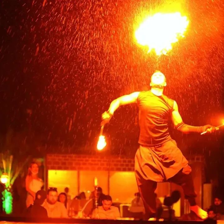 Fire performer entertaining guests at a desert camp at night