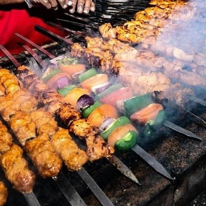 Chicken and vegetable skewers grilling for a desert safari dinner