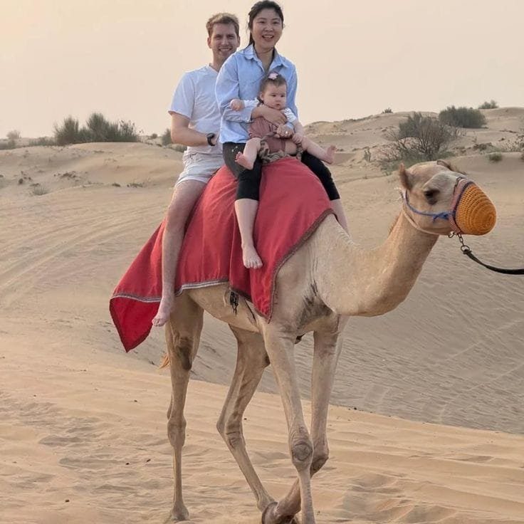 Family riding a saddled camel near the desert camp