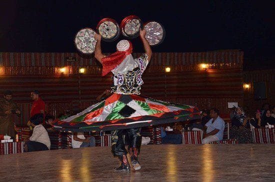 Tanoura dancer spinning a patterned skirt on an illuminated camp stage