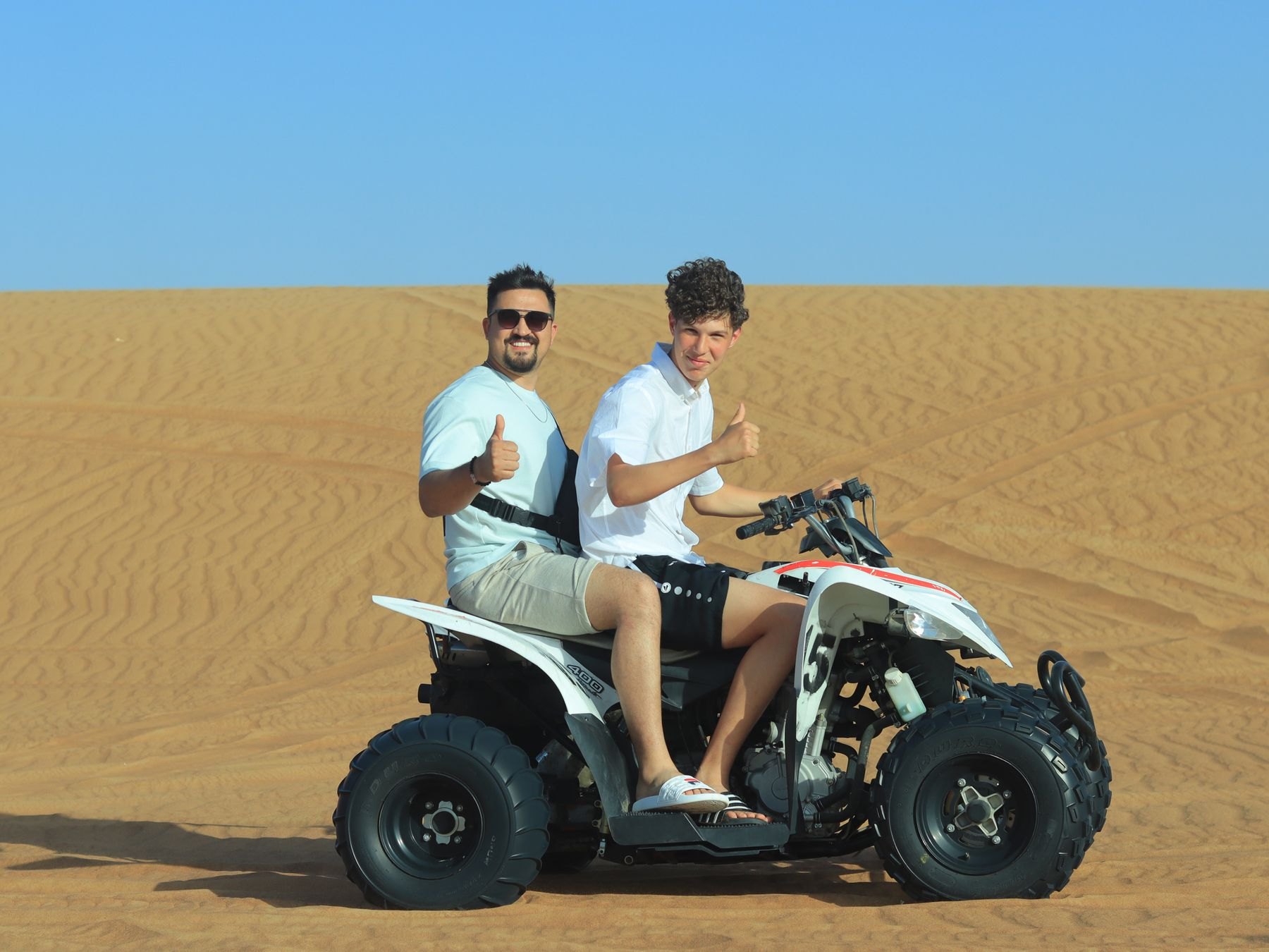 Two men on a quad bike in Dubai desert